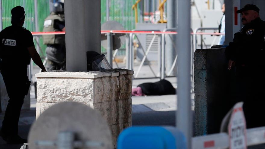 Fuerzas israelíes cerca del cadáver de una mujer palestina a la que asesinaron en un puesto de control entre Cisjordania y Al-Quds, 12 de junio de 2021. (Foto: AFP)