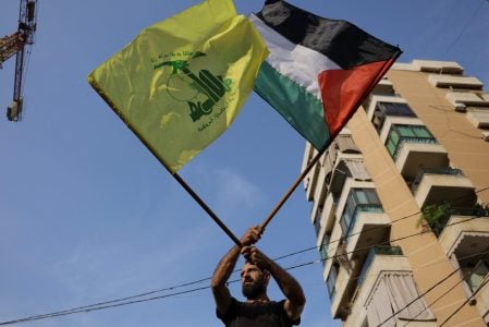 FILE PHOTO: A man holds Hezbollah and Palestinian flags as Hezbollah supporters protest in solidarity with Palestinians in Gaza, amid the ongoing conflict between Israel and Palestinian Islamist group Hamas, in Beirut, Lebanon, October 27, 2023. REUTERS/Amr Alfiky/File Photo